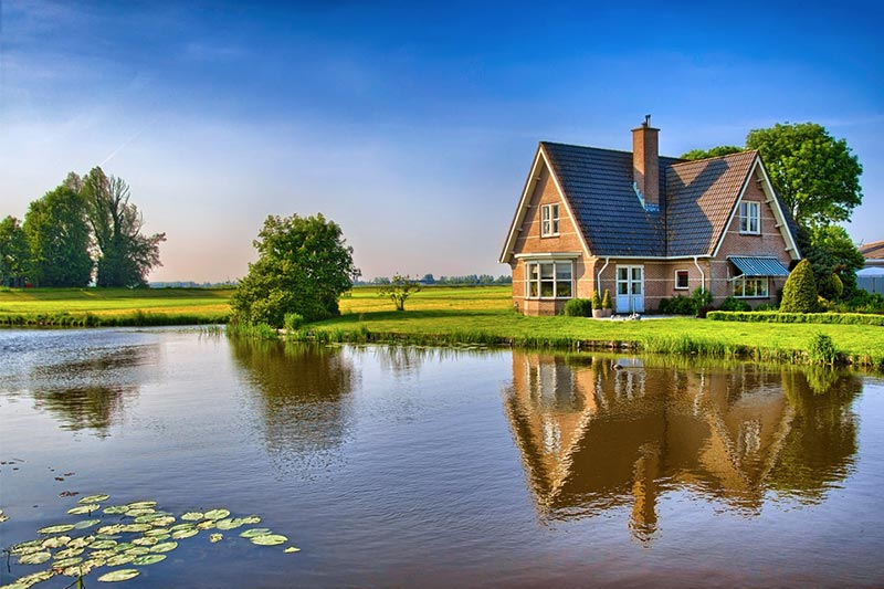 Brick home along pond in open field