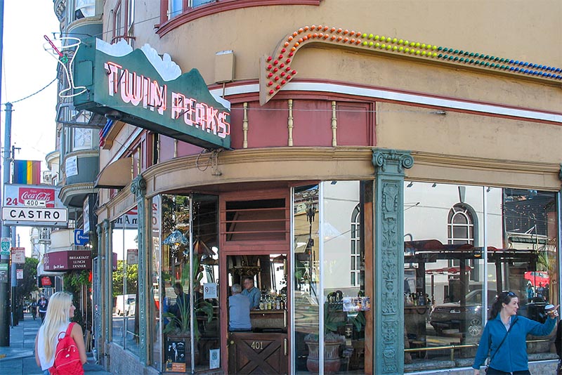 People walk past a wood and glass doorway to a historic bar in San Francisco