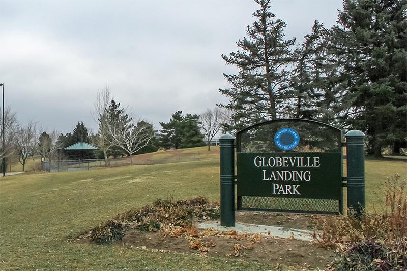 A park entrance sign for Globeville Landing Park sits on a grassy hill in Denver