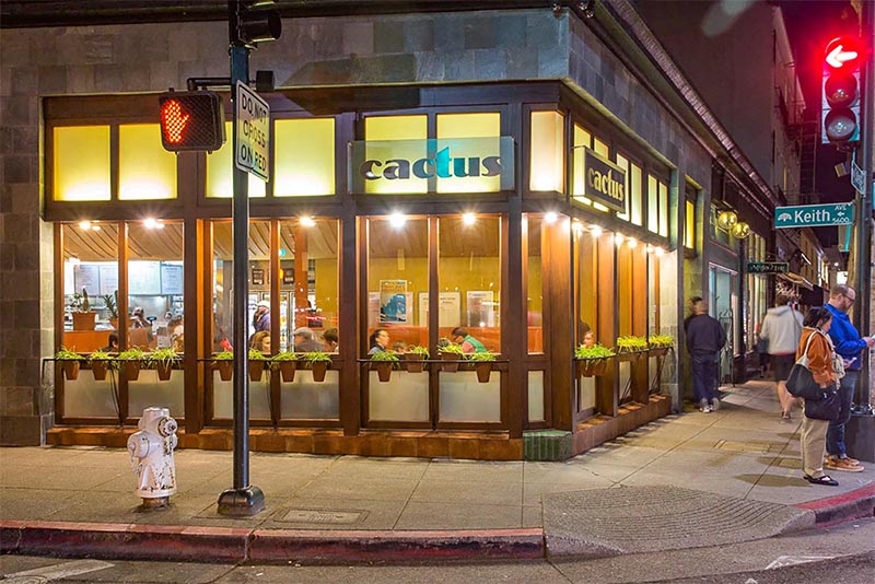 People eating inside large windows at Cactus in Oakland