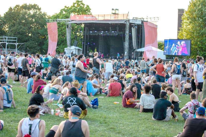 People sitting in the grass at Union Park while Mavis Staples performs during Pitchfork Music Festival