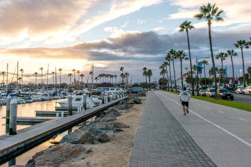 A person running along the path adjacent to the Long Beach Marina. 