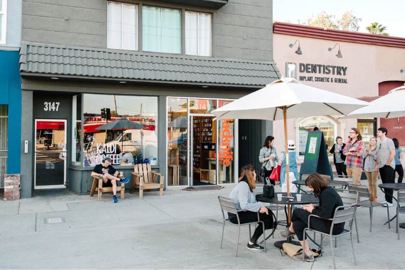 People sitting outside of businesses along Glendale Blvd. 