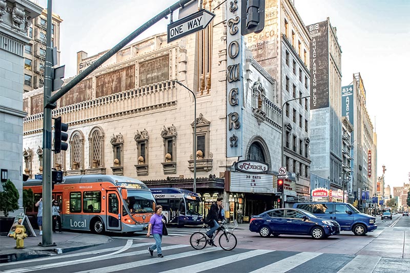 People walking and biking near a busy intersection in Downtown Los Angeles