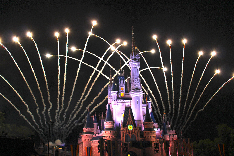 Fireworks going off behind Cinderella's castle at night.