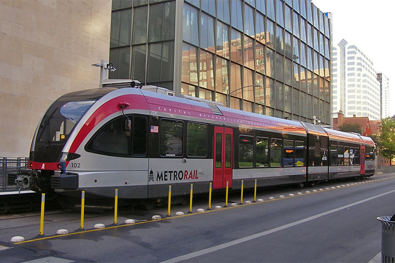 View of Metro Rail train next to buildings in the city. 