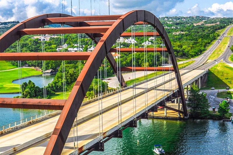 The Pennybacker Bridge in Austin leading out from the city with roads and hills behind it
