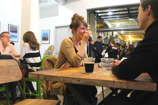 Several people drinking beer at tables in a Begyle Brewery in Chicago, IL.