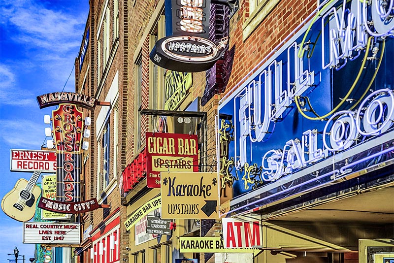 A flat view of neighboring buildings in SoBro Nashville with many colorful neon honky tonk signs