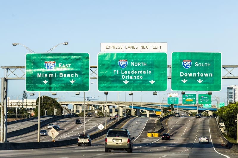 Cars driving on highway towards Miami Beach, downtown, and Fort Lauderdale.