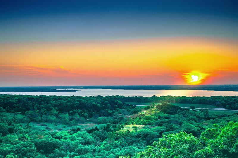 A colorful sunset overlooking a lake in North Texas over the hills of Cedar Hill