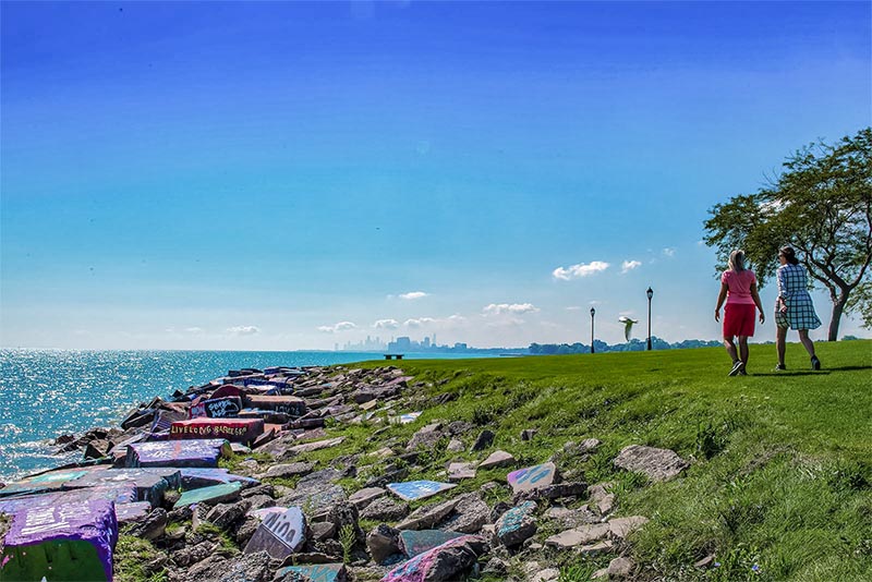 Two people walking along the lakefront in Evanston with the Chicago skyline ahead of them