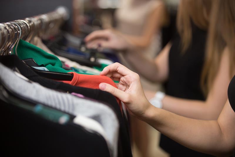 Young women looking through a clothing rack in a thrift store