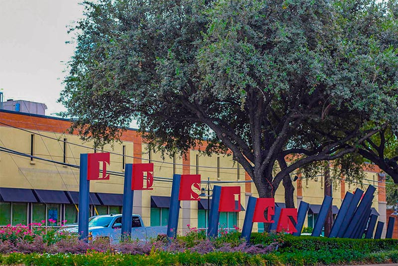 A sign in Dallas Texas that says Design District near a tree