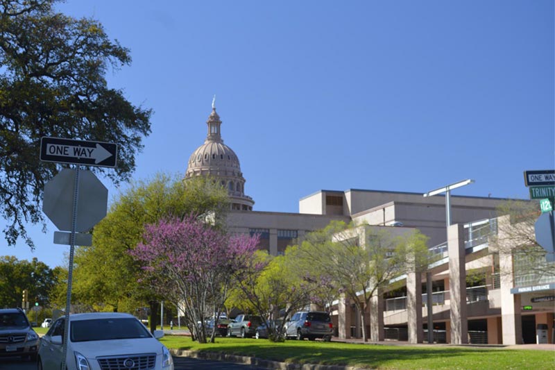 Exterior of Austin capitol building with park.