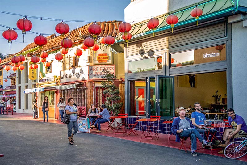 People sitting on patios and walking through Chinatown streets in Downtown Los Angeles