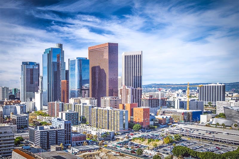 An aerial view of the skyline of Downtown Los Angeles against a blue sky