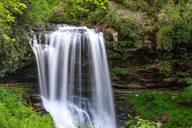 A large waterfall juts out from the cliff face in North Carolina