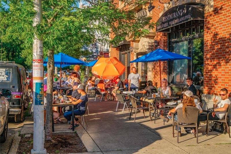 outdoor patio with peaople drinking and eating in neighborhood