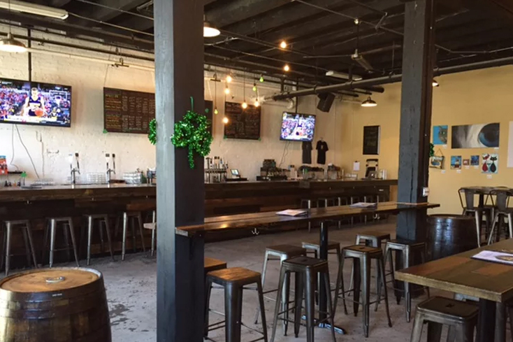 Empty bar and bar tables with televisions above bar at Empirical Brewery.