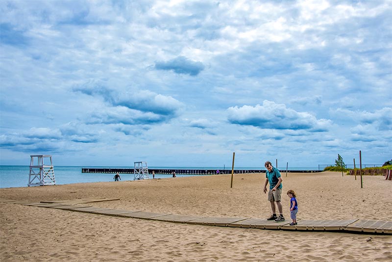 An adult and a child walk along the beach in Evanston