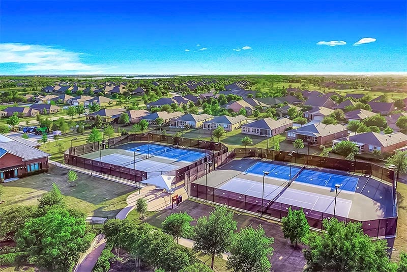 An aerial view of new construction homes in front of tennis courts in Frisco