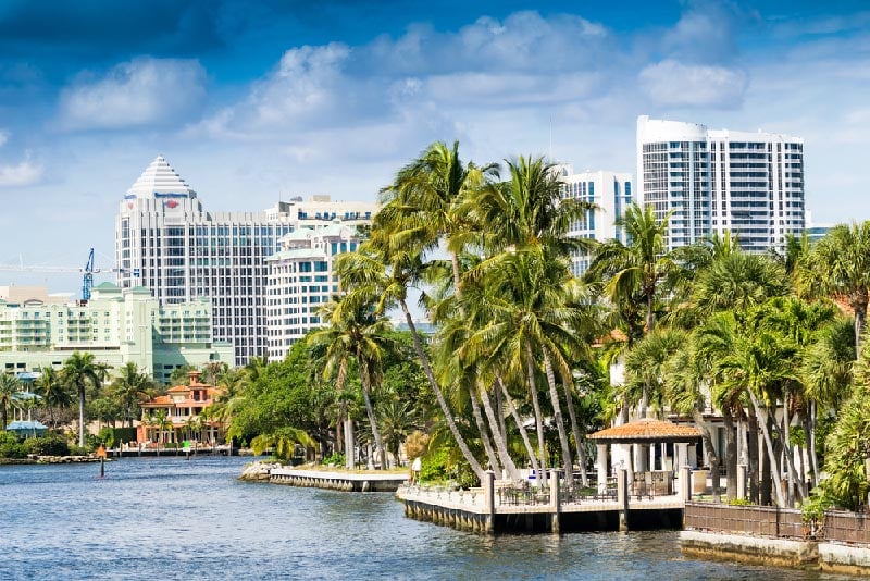 Homes and boats along waterway with Fort Lauderdale skyline in background.