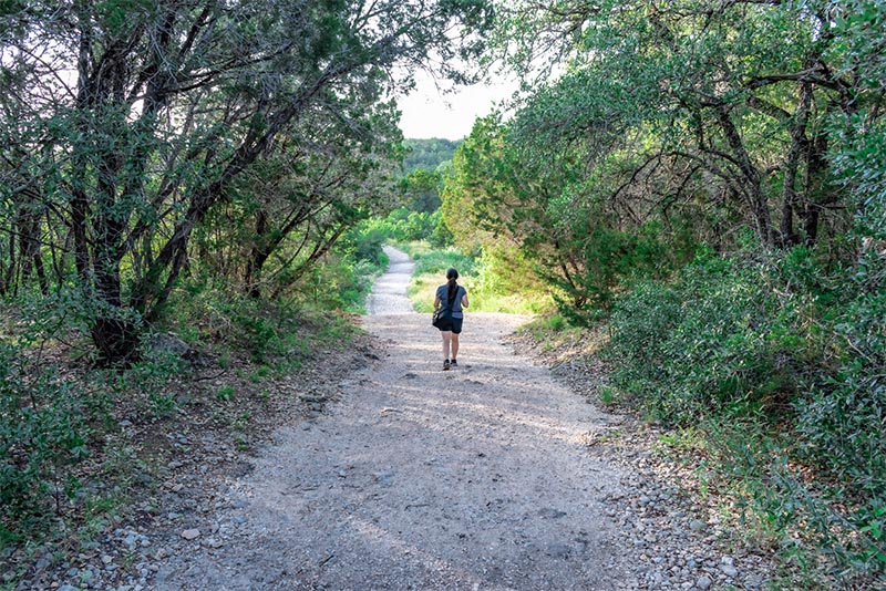 A hiker walks down the middle of a trail in Government Canyon State Park