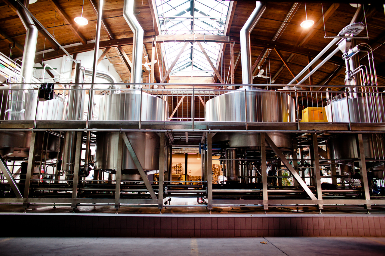 A row of steel beer tanks in a warehouse style brewery.