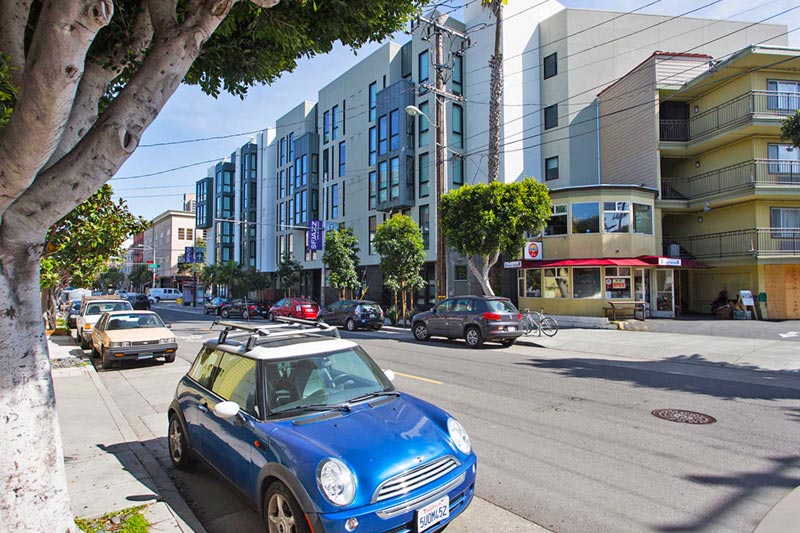 car parked along neighborhood street with buildings in background