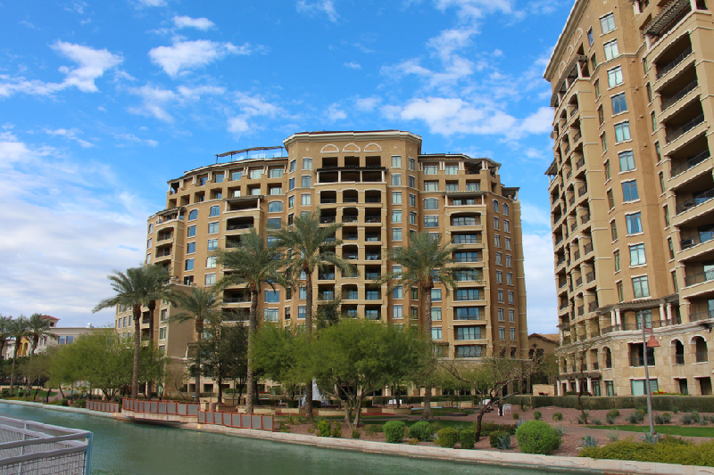 Mid-rise condo buildings along scenic canal with palm trees.