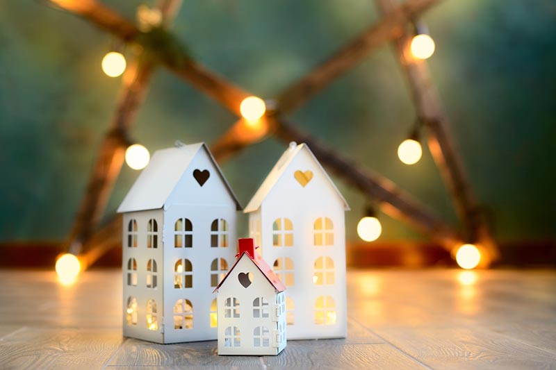 Miniature houses on a wood floor in front of a lighted decoration