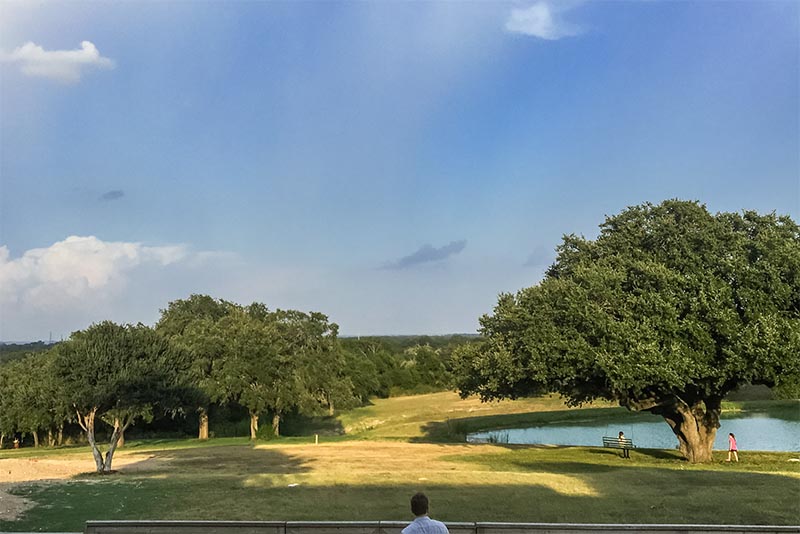 People walking around a park with a pond in Hutto Texas