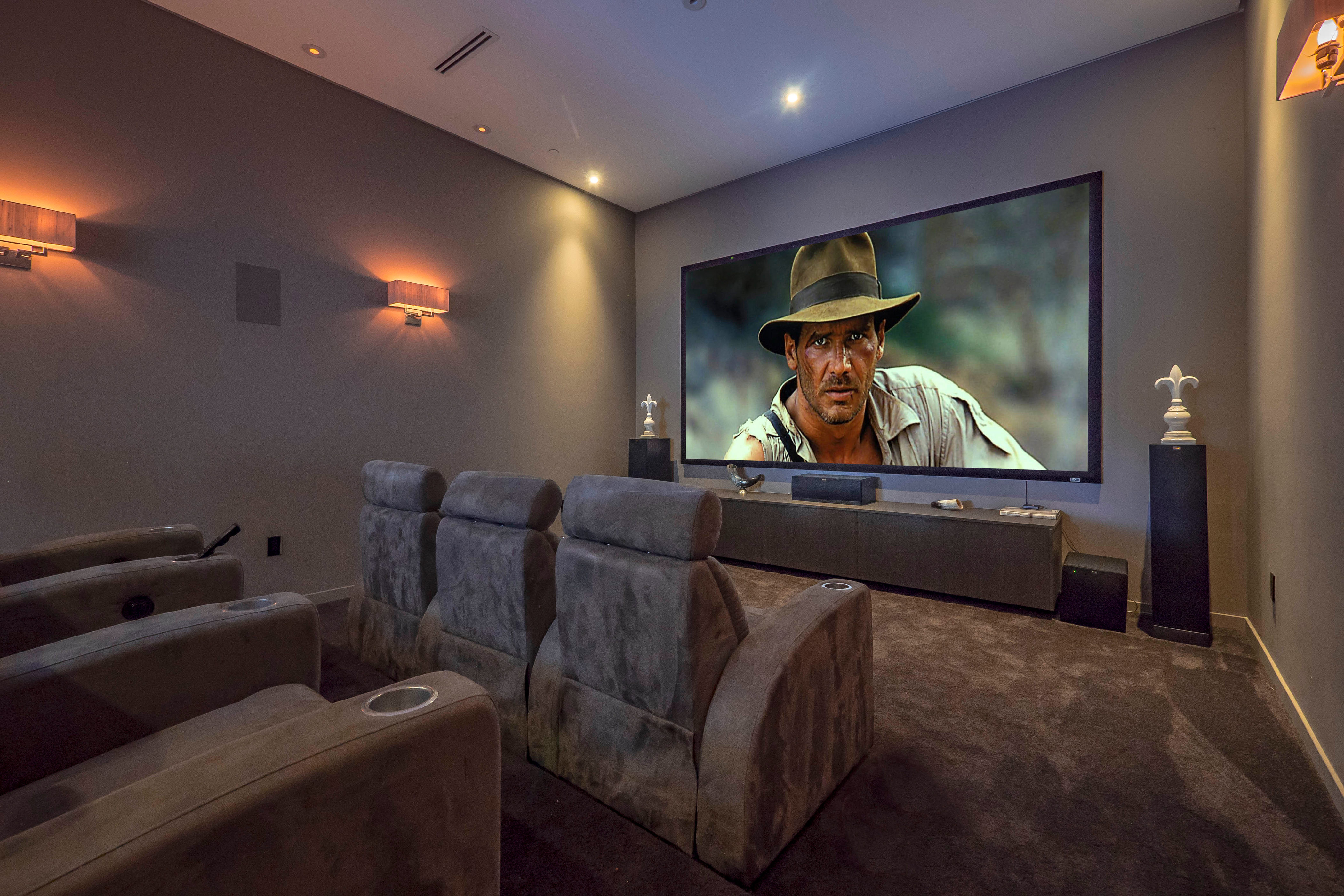 Interior of a luxurious home theater with Harrison Ford's Indiana Jones playing on the TV