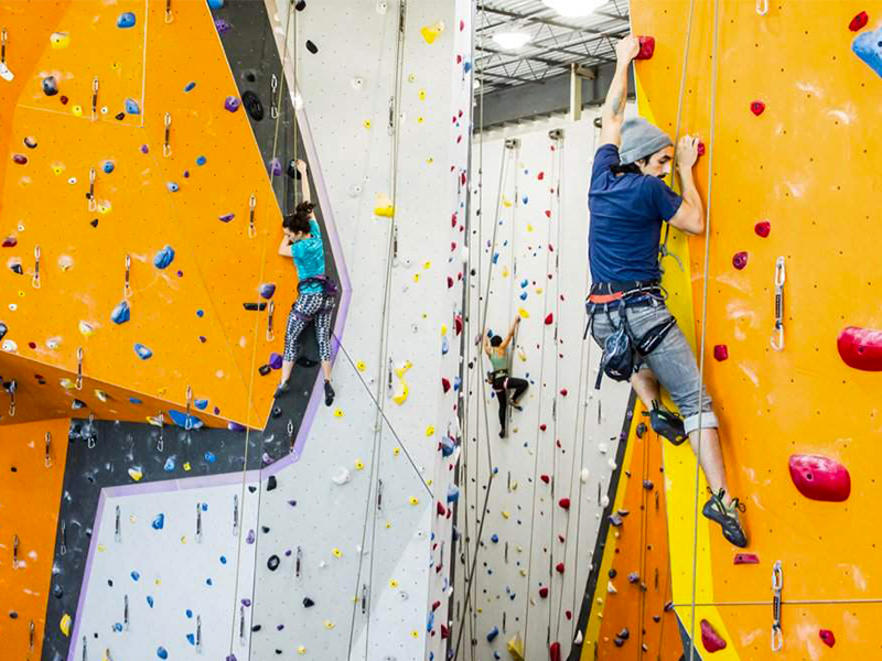 Person climbing indoor colorful rock climbing wall at First Ascent in Chicago.