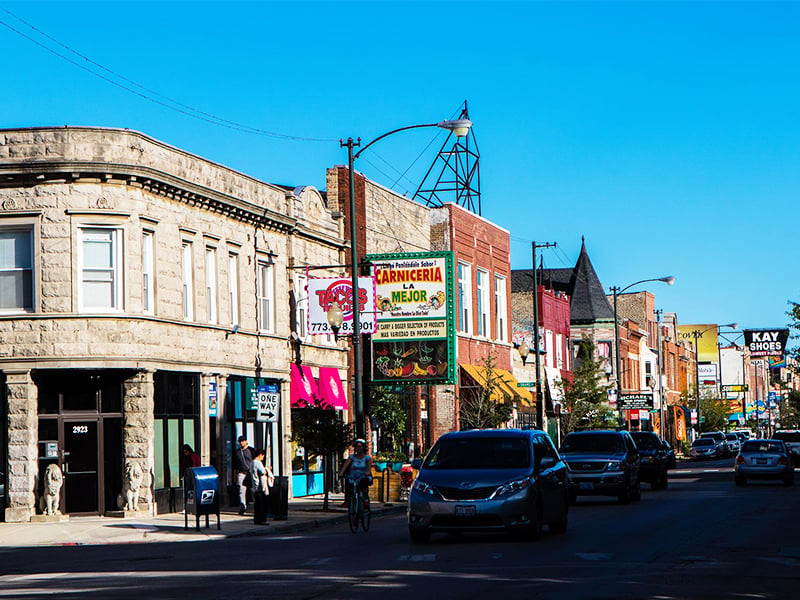 Street scene with line of restaurants and colorful signs in Chicago's Avondale neighborhood.