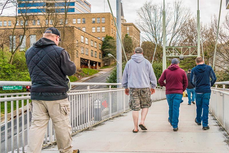 A group of people walk across a pedestrian bridge in Knoxville