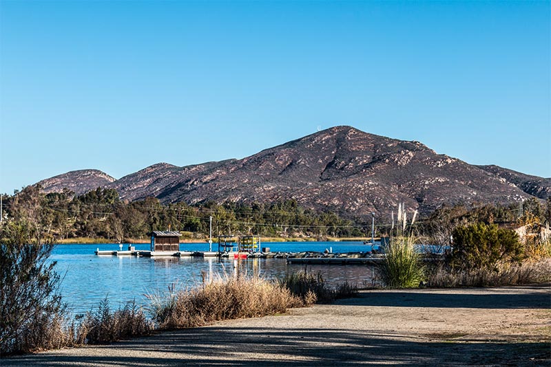 A trail along Lake Murray with a boat launch and a mountain rising in the background in San Diego