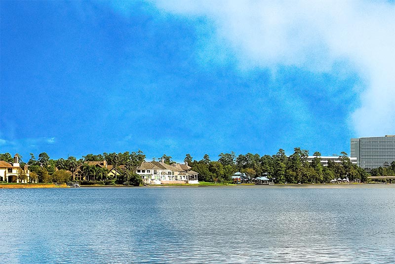 Lake Woodlands in front of large mansion-style homes with blue skies above