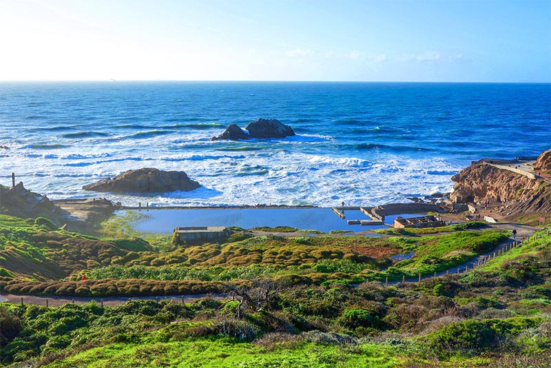 A view looking towards the ocean of tourists at Lands End Trail on the cliffs of San Francisco