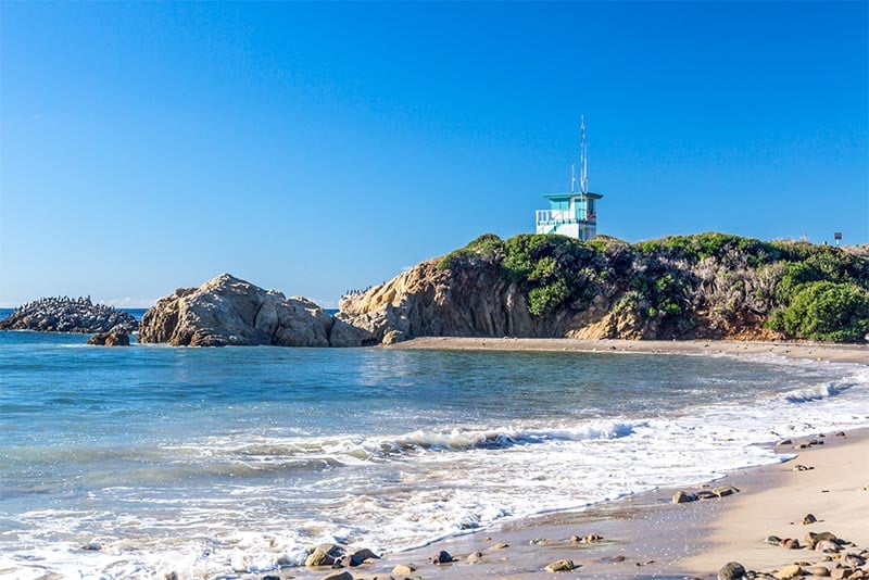 A beachfront with a cliff in the background and a lighthouse above in Los Angeles