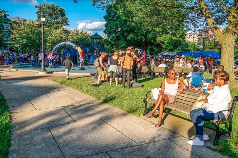 busy park with children playing and women talking on bench