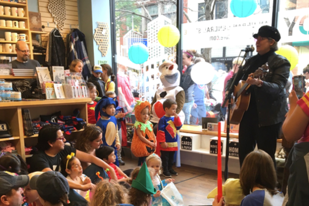 Women singing to group of kids dressed up for Halloween.