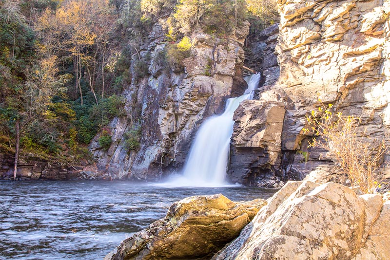 A tall waterfall crashes into the basin below surrounded by cliff faces in the Charlotte area