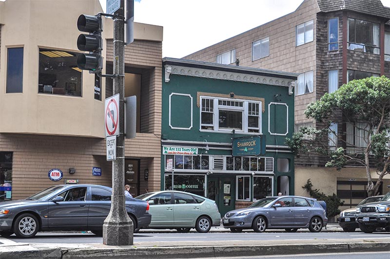 A row of businesses including historic bars in San Francisco along a street with cars