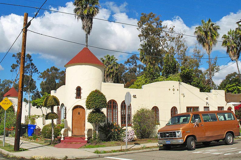 Exterior of stucco home with car out front and bright accent colors.