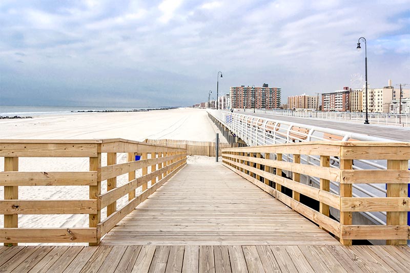 A wooden ramp entrance to Long beach New York with a boardwalk next to it