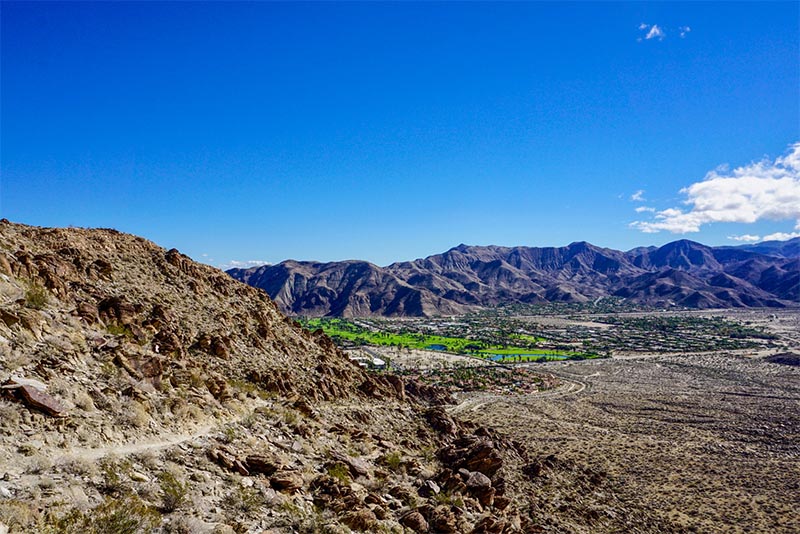 A view from high up on a cliff of a city down below in Palm Springs California