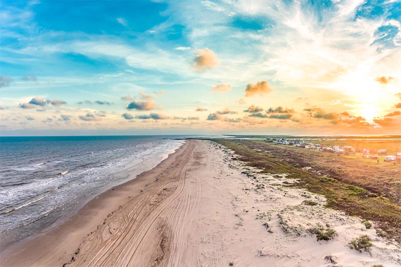 A typical beach scene with the Gulf washing in from the left and beach sand on the right in Matagorda Texas.