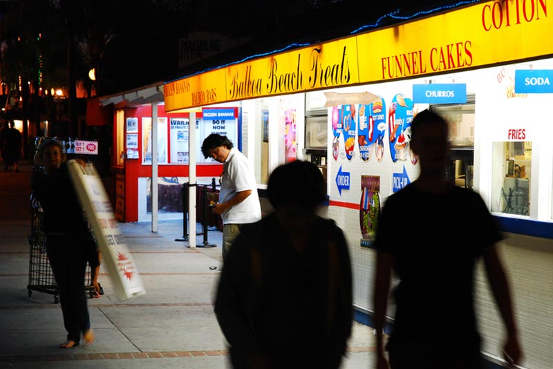 Two teenagers walk past Balboa Treats at night on Balboa Island in Newport Beach, California